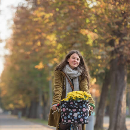 A woman taking an afternoon stroll through the park with a bouquet of flowers in hand