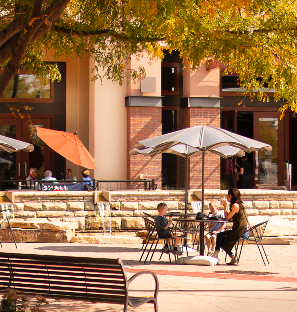 A mother and her two boys take a break from shopping and relax at an outside table in the Promenade Shops at Centerra