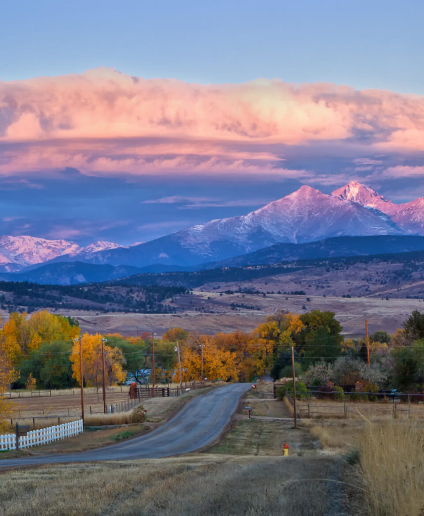 Scenic road with fall trees and a mountain view in the distance that can be enjoyed in Loveland, Colorado