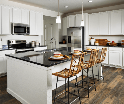 A Lennar kitchen with bright white cabinets surrounding a dark granite island and countertop seating