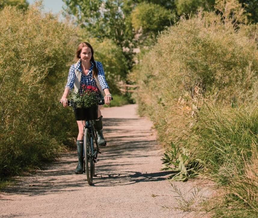 A woman riding her bicycle along a trail in Centerra following the lake shoreline