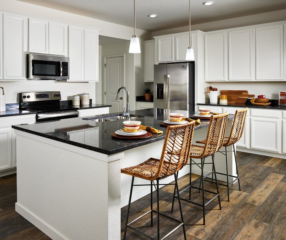 A kitchen with white cabinets and black counter tops.