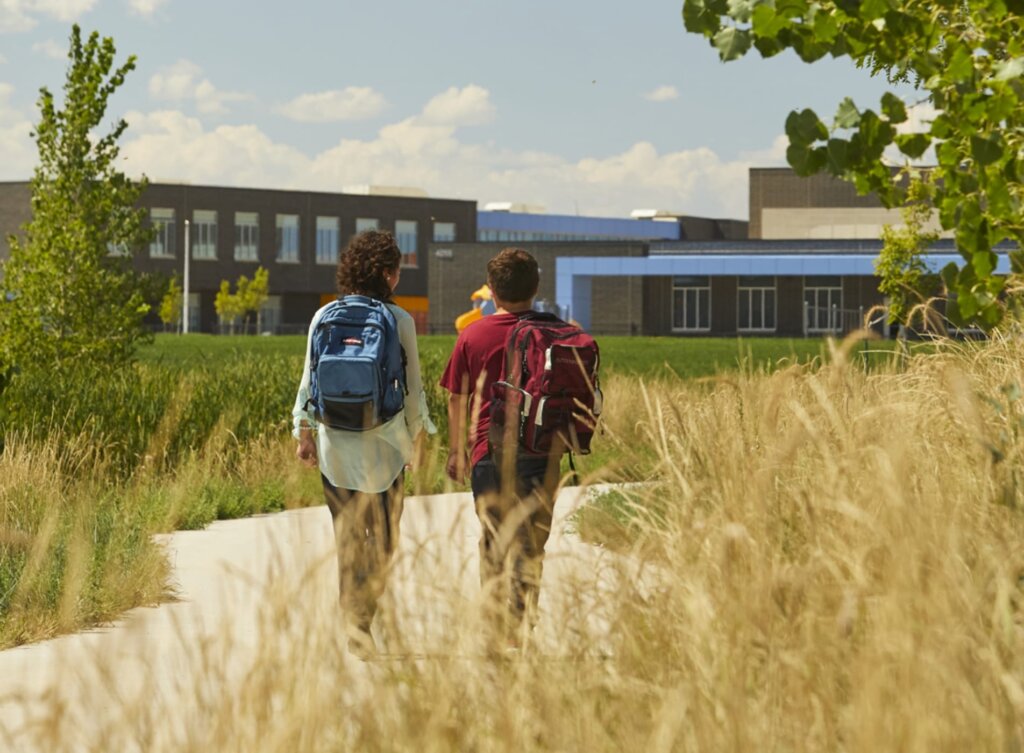 Two students walking down a path in tall grass.