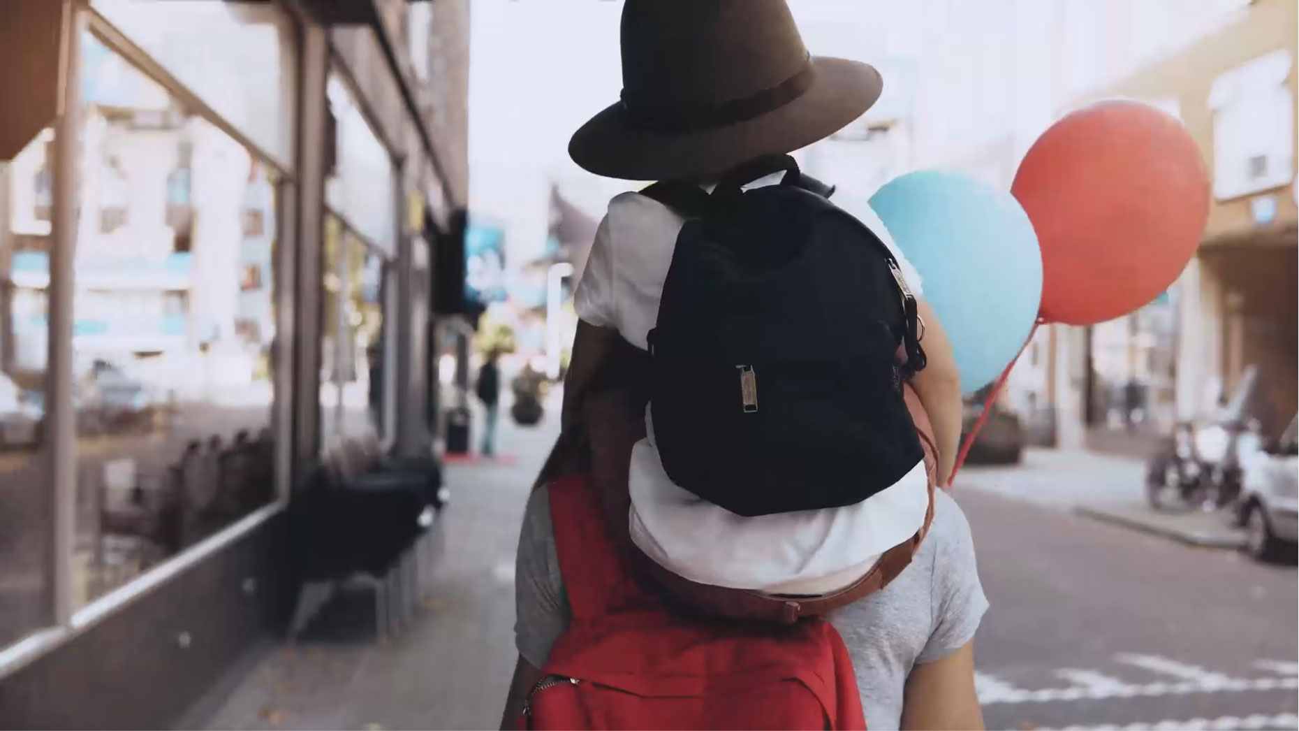 Father with son on his shoulder walking down the street.