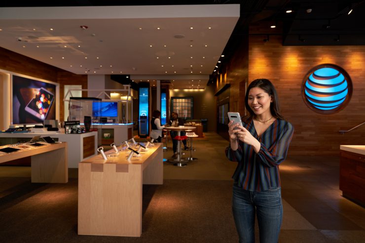 Image of the inside of an AT&T store with a woman holding up a phone