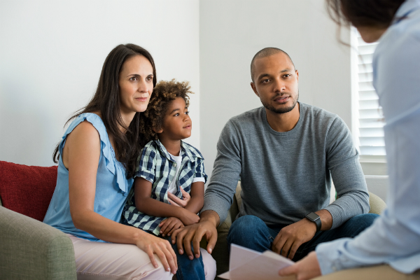 Image of a family sitting on a couch across from a counselor