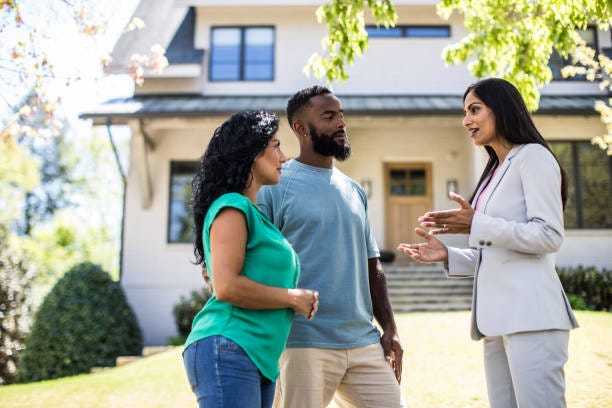 Image of a couple talking to a realtor outside of a home
