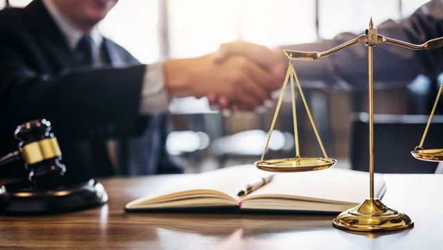 Image of two men shaking hands with a gavel in the foreground