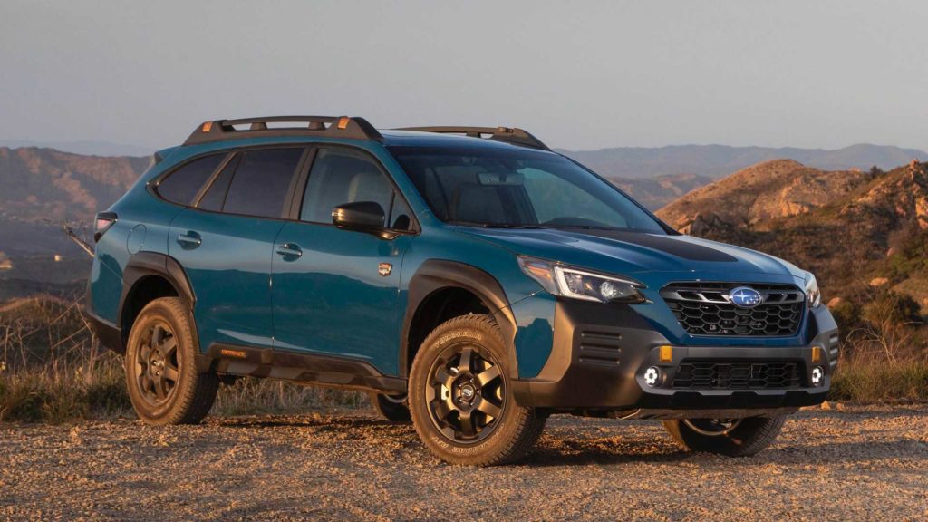 Image of a blue Subaru outback with mountains in the background