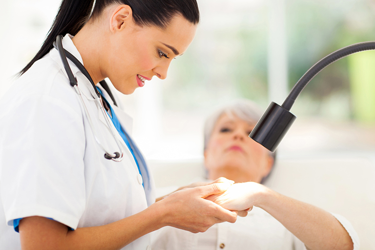 image of a friendly dermatologist examining senior woman's skin under light