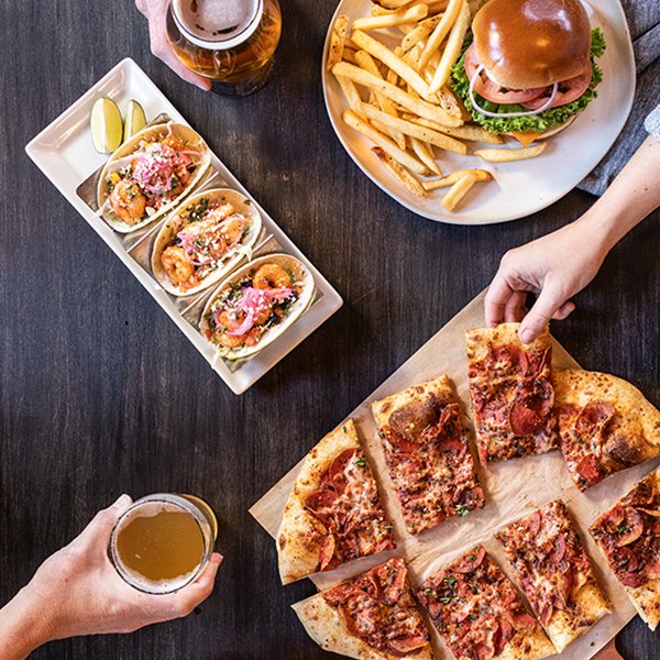 Image of plates of a burger and fries, tacos, and a pizza from Rock Bottom Brewery