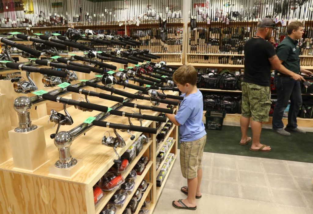 Image of young boy looking at fishing rods at Sportsmans Warehouse