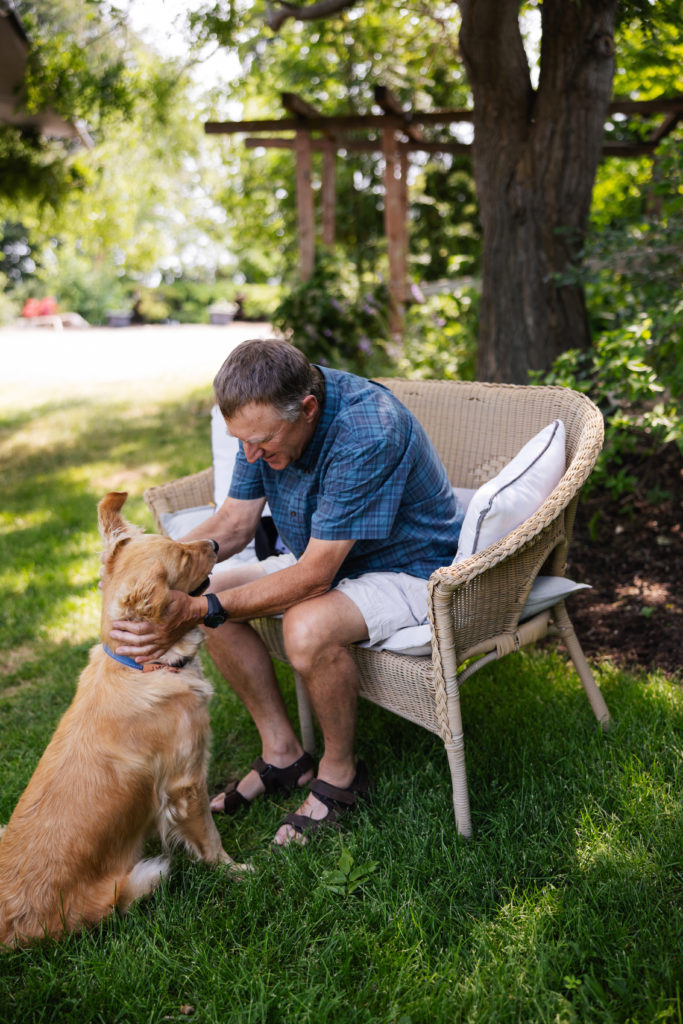 Mature man petting dog while sitting outside