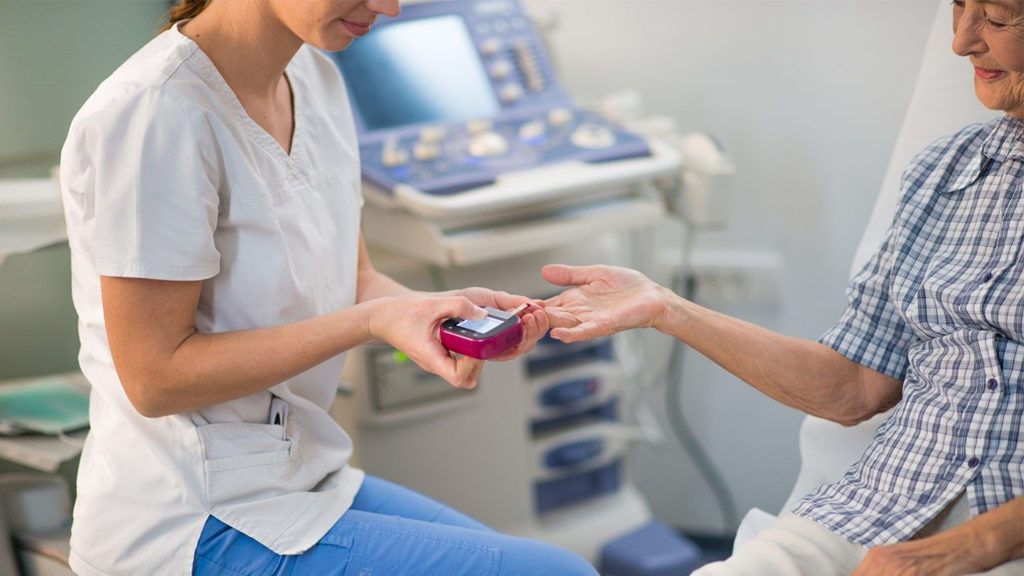 Image of senior woman getting her finger pricked by a nurse