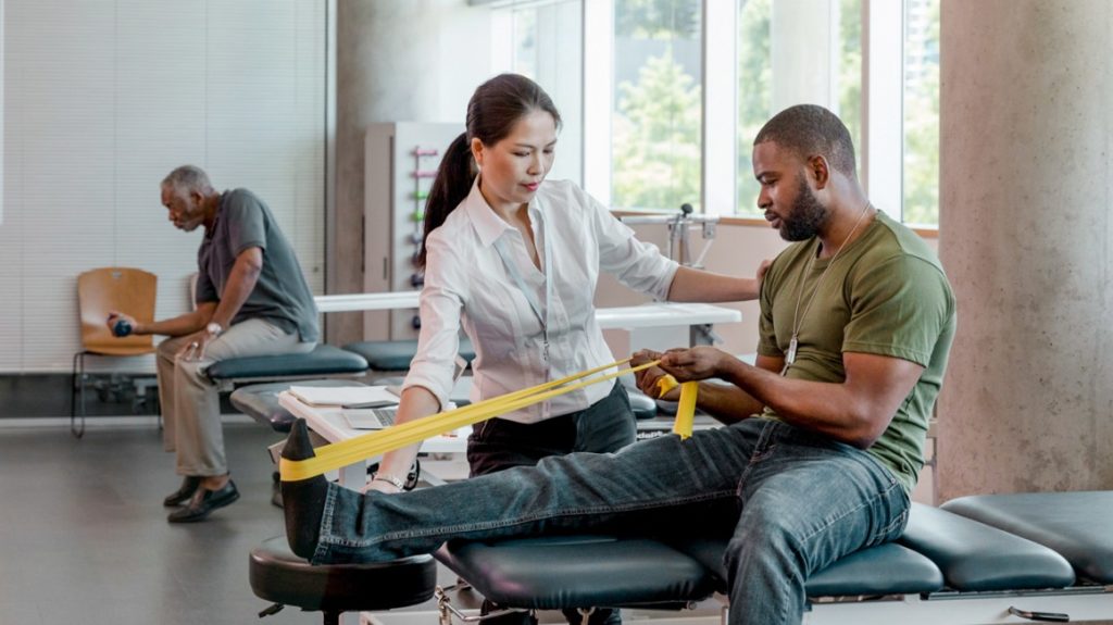 Image of man using a band to stretch his leg at UCHealth Orthopedics Clinic