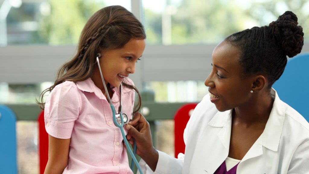 Image of a doctor holding up a stethoscope to a young girls chest