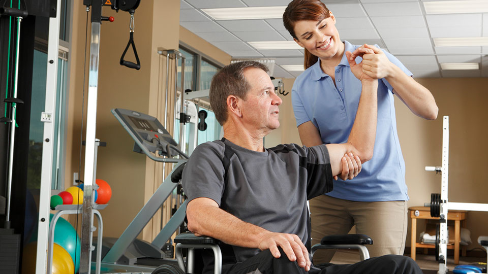 Image of man working with a happy female physical therapist