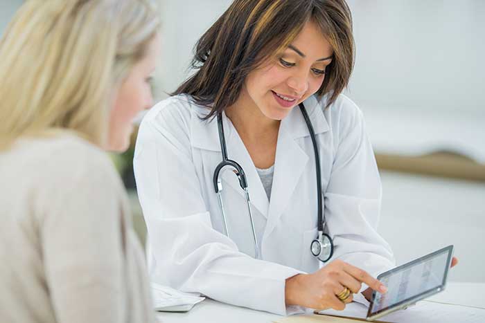 Image of female doctor showing an tablet to a female patient
