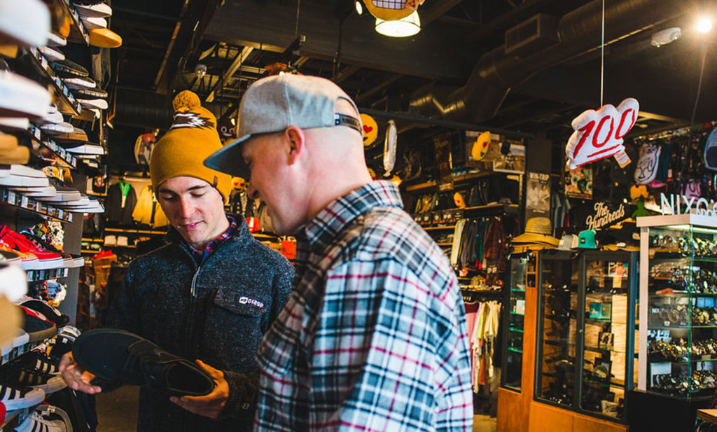 Two men shopping for shoes in a store.