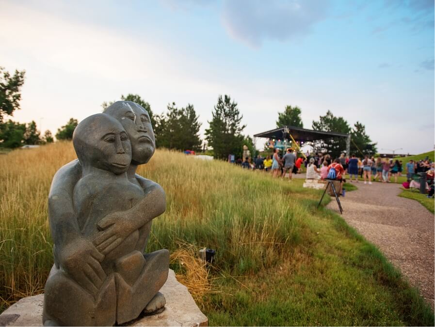Image of sculpture of two hugging people with concert in the background