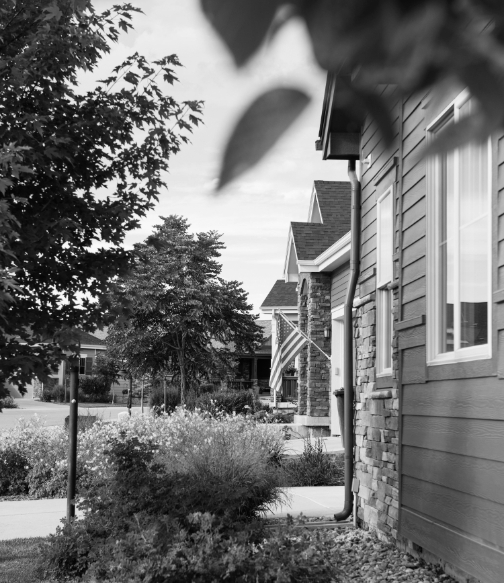 Black and white image of the front of homes with a hanging American flag