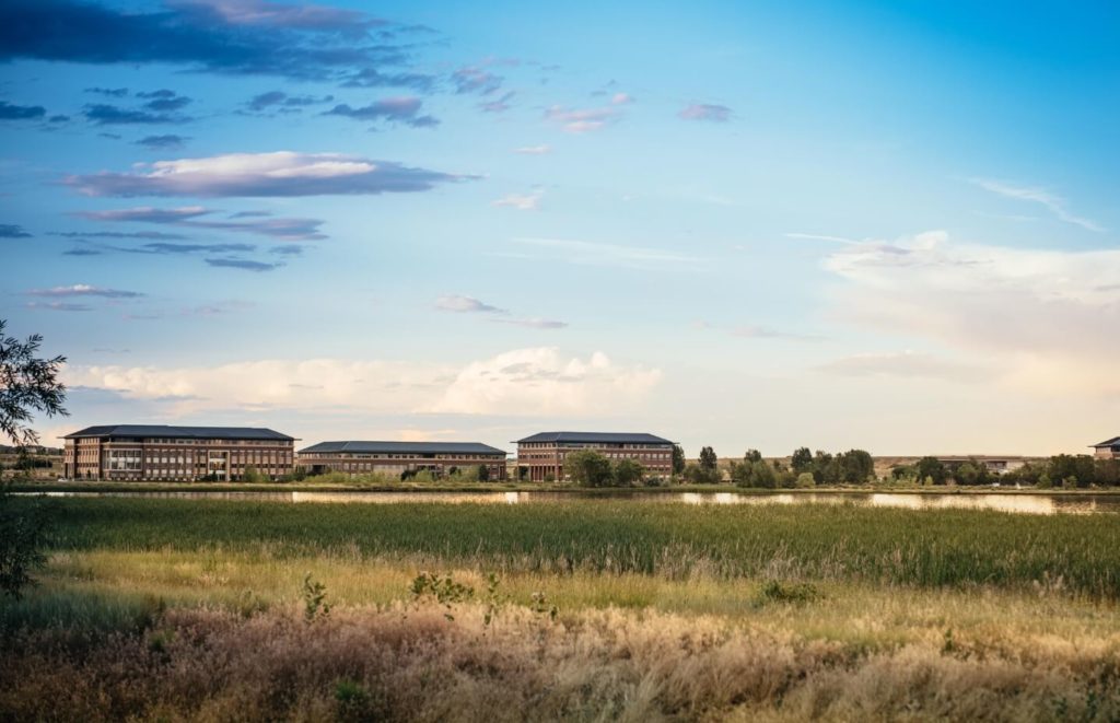 A group of **new homes** nestled in a field near a lake, offering residents the opportunity to enjoy the serene beauty of **Northern Colorado** while also being in close proximity to various options