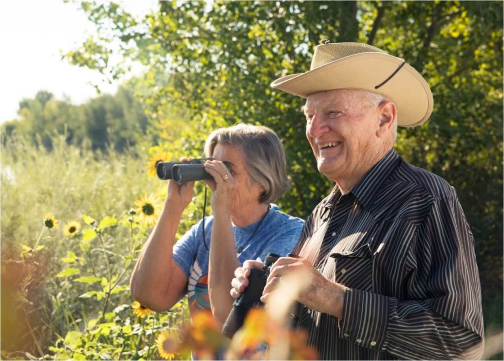 A man and a woman, both wearing cowboy hats, are seen using binoculars while exploring the beautiful landscapes of Northern Colorado.