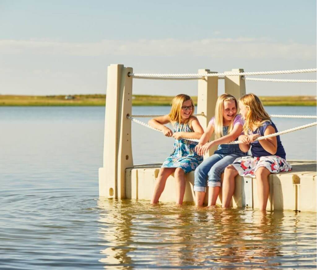 Three girls sitting on a dock in the water in Northern Colorado.