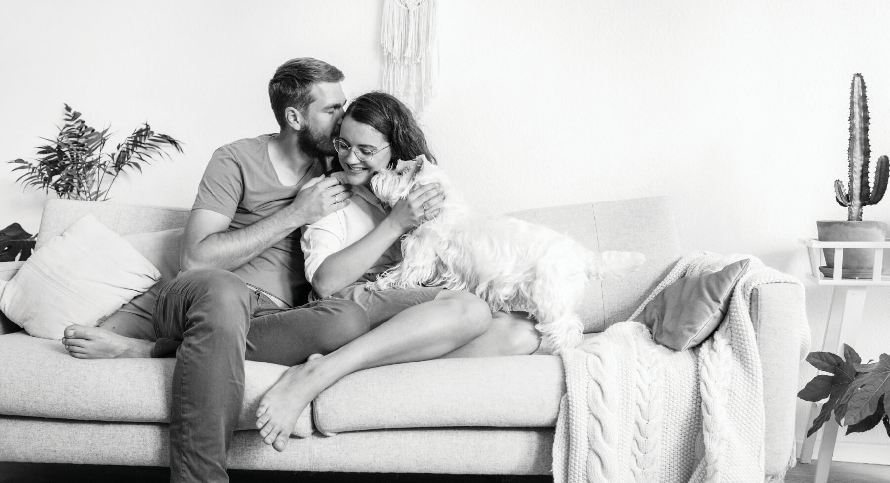 Black and white photo of a couple sitting on a couch in their new home.