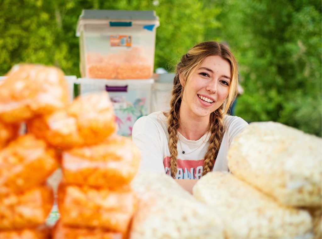 A woman smiles while standing in front of a pile of popcorn at a shopping mall.