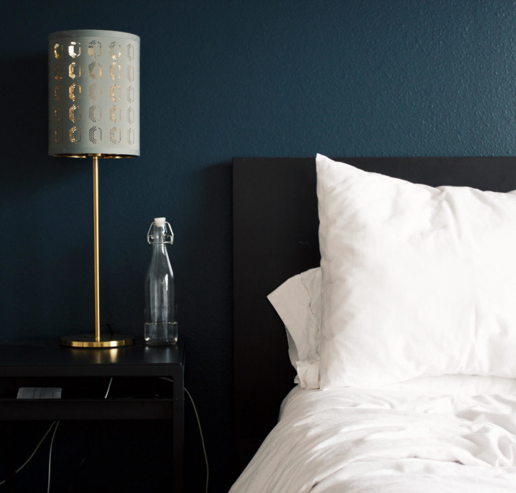 A bed with white sheets and a lamp next to it in a New Home in Northern Colorado.