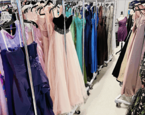 Racks of formal dresses in various colors and styles hang on hangers in a brightly lit room with a light floor, echoing the elegance and diversity often found in new homes within a master-planned community.