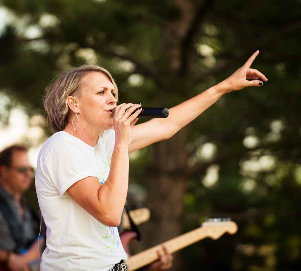 A woman singing into a microphone at a concert in Loveland, Northern Colorado.