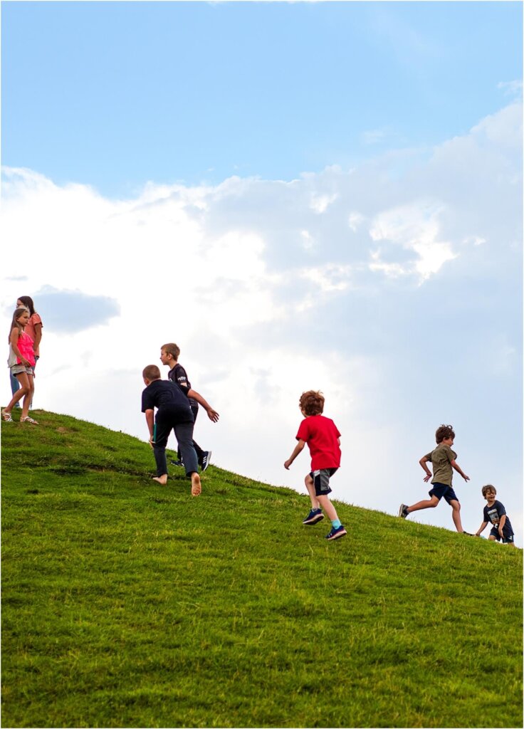 A group of children running on a grassy hill in Northern Colorado.