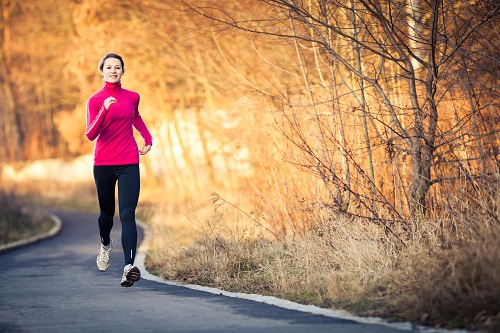 Young woman running outdoors in a city park on a cold fall or winter day (motion blurred image)