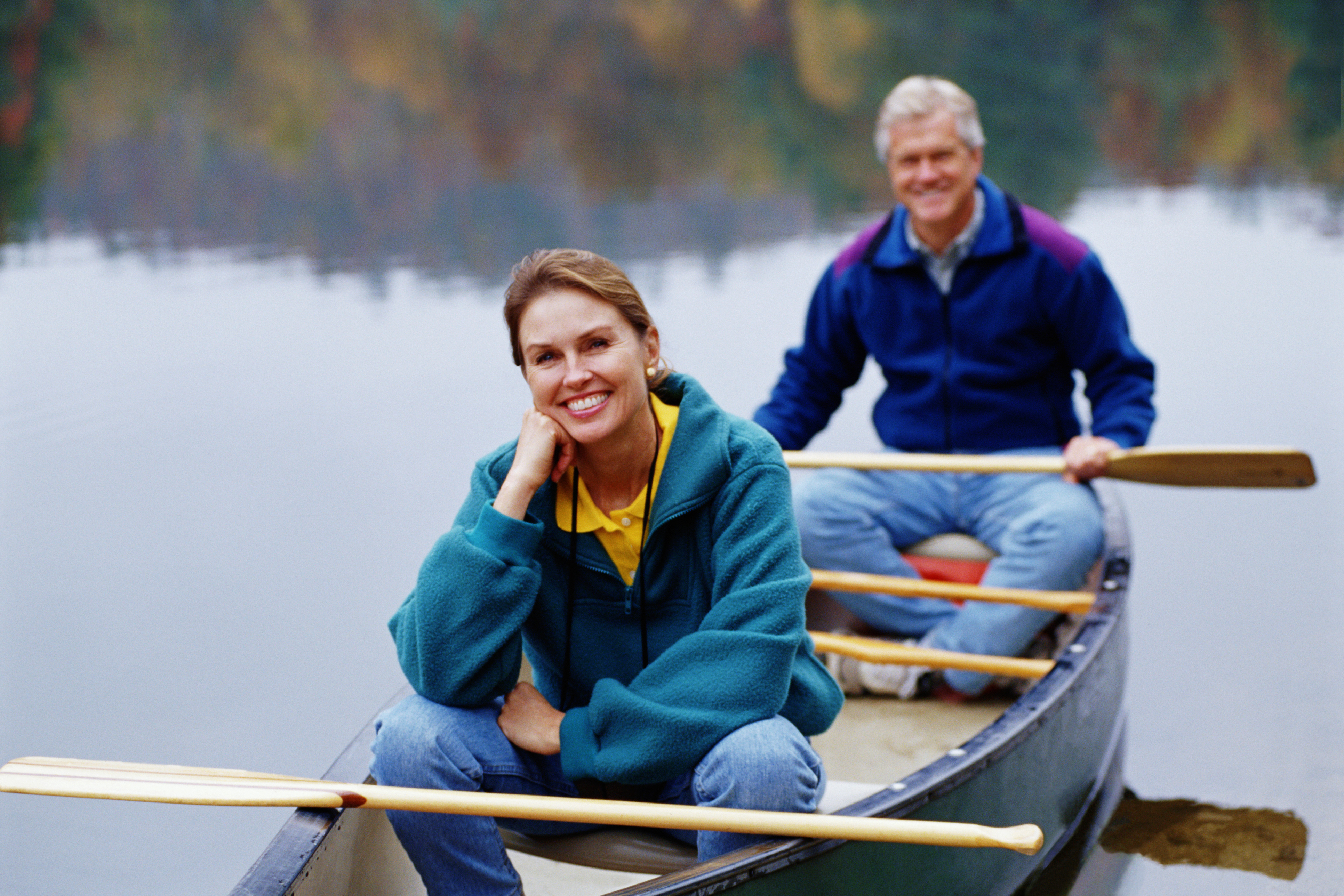 Close-up of couple sitting in canoe, both with paddles in laps