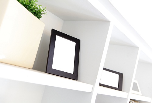 blank photo frame with copy space on white bookshelf at home